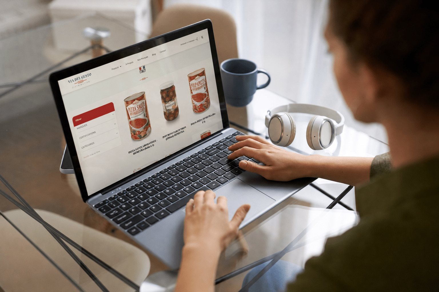 Une femme de dos en train de passer commande en ligne sur le site de Via Del Gusto